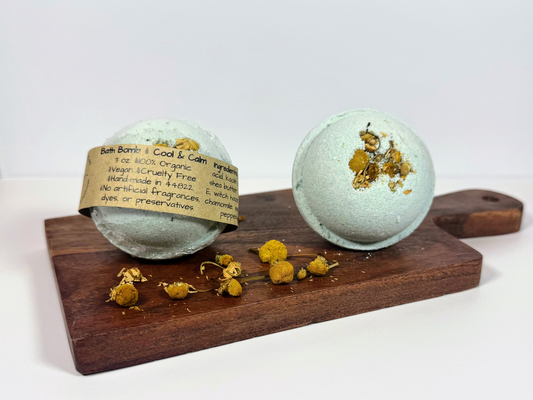 Two bath bombs with Chamomile flowers on a wooden board against a white background